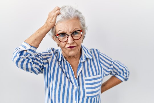 Senior woman with grey hair standing over white background confuse and wonder about question. uncertain with doubt, thinking with hand on head. pensive concept.