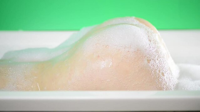 young caucasian woman hips in bath foam at green screen background
