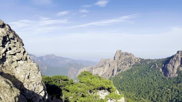 Very rocky Corsican mountain range of the Aiguilles de Bavella in summer, very tall and wide massif of France, near Zonza in Conca forest, with some trees in bottom