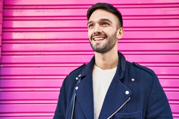Young hispanic man smiling confident looking to the side over isolated pink metalic background