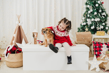 smiling child girl at home standing with dog during christmas time