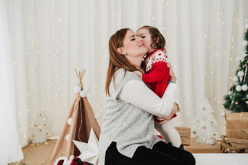 cute child kissing and embracing mother. enjoying christmas time at home