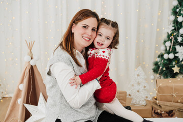 happy mother and daughter embracing at home during christmas time