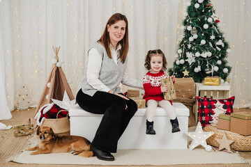 happy mother and daughter at home during christmas time. child holding presents