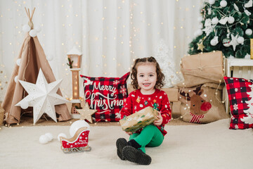 adorable little girl at home holding gifts during christmas time