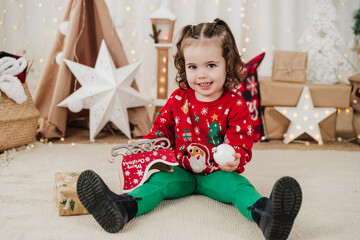 happy little girl at home holding presents during christmas time