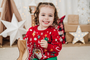 cheerful little girl at home holding presents during christmas time