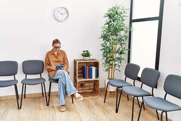 Young blonde woman smiling confident using touchpad at waiting room