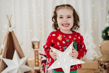smiling little girl at home holding star during christmas time