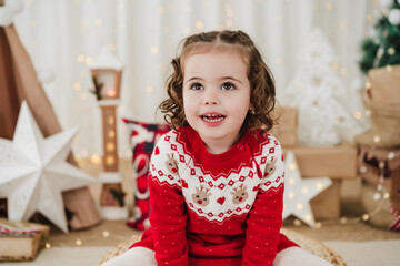 smiling cute little girl at home during christmas time sitting on stool