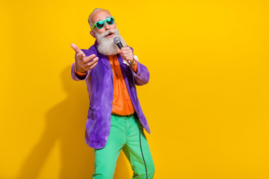 Photo of funny charming man wear purple velvet jacket enjoying karaoke pointing you arm empty space isolated yellow color background - Powered by Adobe