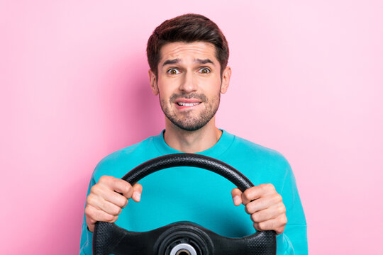 Photo portrait of attractive young guy hold steering wheel bite lips confused wear trendy blue garment isolated on pink color background