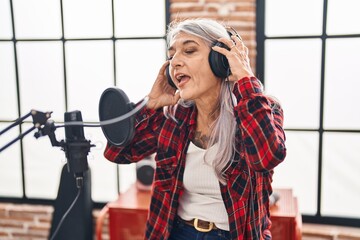 Middle age grey-haired woman artist singing song at music studio