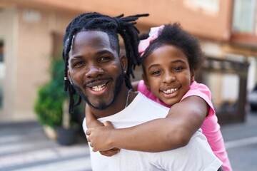 Father and daughter smiling confident holding girl on back at coffee shop terrace