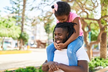 Father and daughter smiling confident holding girl on shoulders at park