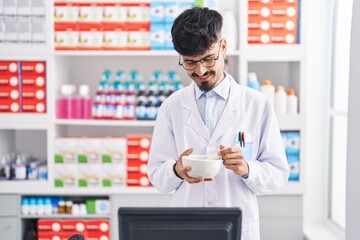 Young hispanic man pharmacist smiling confident working at pharmacy