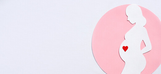 Paper silhouette of a pregnant woman in a pink circle on a white background. Banner, flat lay, space for text.