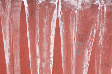 Fototapeta premium large icicles on a red background. Winter and frosts