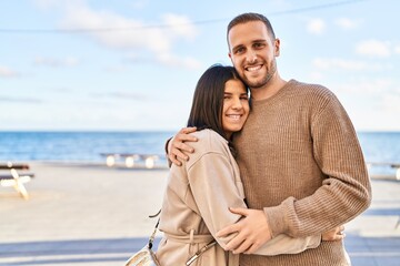 Man and woman couple smiling confident hugging each other standing at seaside