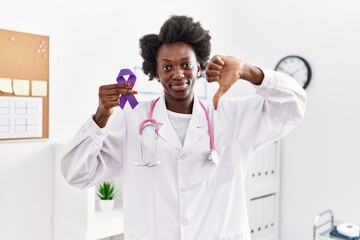 African doctor woman holding purple ribbon awareness at medical clinic with angry face, negative...