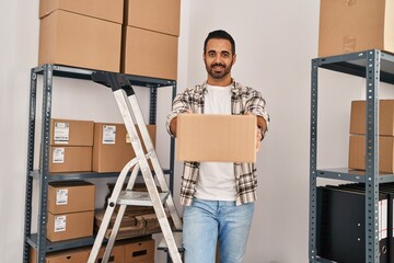 Young hispanic man ecommerce business worker holding package standing at office