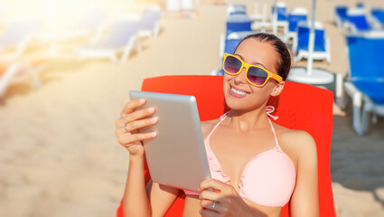 Woman with a tablet pc or smartphone on the beach. Vacation.