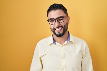 Hispanic young man wearing business clothes and glasses winking looking at the camera with sexy...