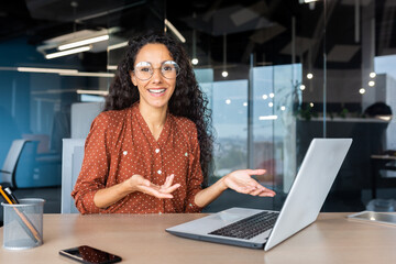 Portrait of happy and successful businesswoman, Hispanic woman smiling and looking at camera...