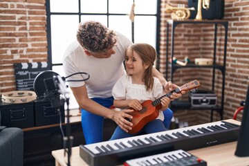 Father and daughter playing ukulele at music studio