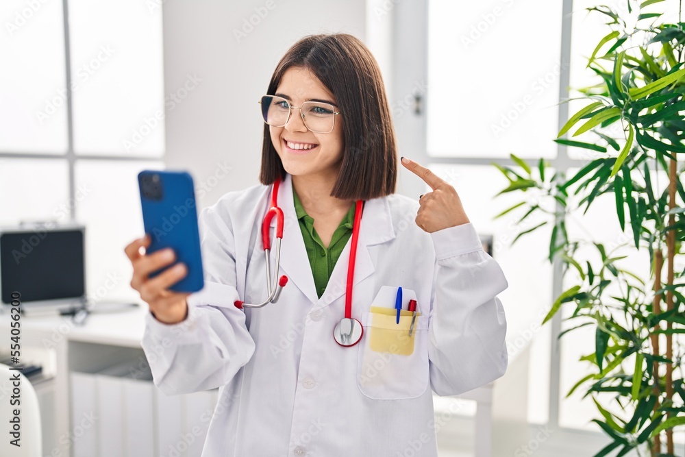 Poster young hispanic doctor woman working on online appointment smiling happy pointing with hand and finge