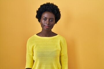 Fototapeta na wymiar African young woman standing over yellow studio relaxed with serious expression on face. simple and natural looking at the camera.