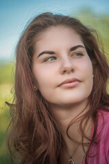 Portrait of a young beautiful long-haired girl on a summer day in sunny weather.