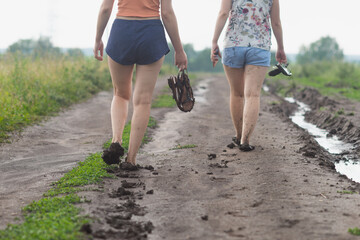 Two young girls walk along a muddy dirt road after the rain. - Powered by Adobe