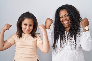 Mother and young daughter standing over white background celebrating surprised and amazed for...