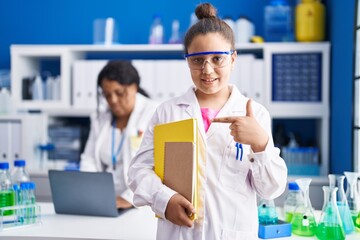 Mother and young daughter working at scientist laboratory smiling happy pointing with hand and finger