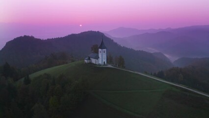 Aerial drone view of small beautiful church on a mountain in Slovenia at dawn. Beautiful autumn morning landscape