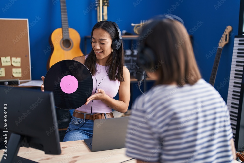 Wall mural two women musicians listening to music holding vinyl disc at music studio