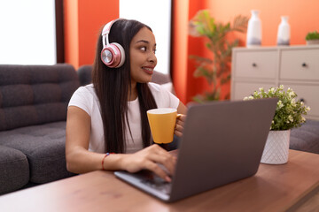 Young arab woman listening to music drinking coffee at home
