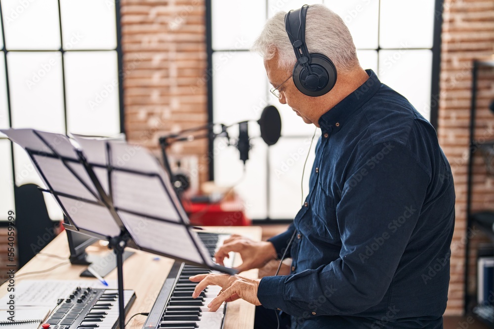 Wall mural Senior man musician playing piano keyboard at music studio