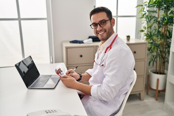 Young hispanic man wearing doctor uniform working at clinic