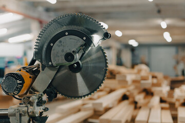 A miter saw in a factory house with a pile of wood chips in the background