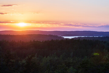 View of the sun setting over the forest and sea. Lemland, Åland Islands. Finland.