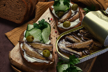 Sandwiches , black bread with sprats, cream cheese, cucumbers, on a cutting board, top view, close-up, no people,