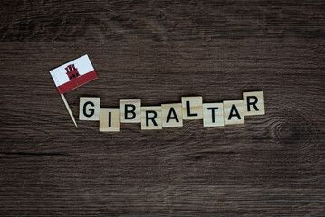 Fototapeta na wymiar Gibraltar - wooden word with gibraltar flag (wooden letters, wooden sign)