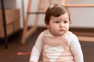 Fototapeta premium Adorable toddler sitting on floor with serious expression at home
