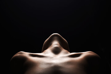 shoulders of a naked woman. Nude silhouette under light in the dark - 554061844