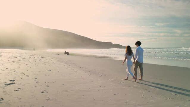 Tourist Couple Holding Hands While Walking On A Summer Beach In Praia de Caion, Spain. Tracking Shot