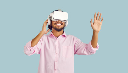 Virtual reality technology. Joyful young man enjoying using virtual reality glasses on pastel light...