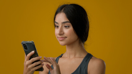 Close up Indian ethnic woman girl lady female smile browsing cell smartphone looking at camera with...
