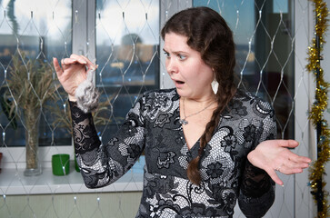 Frightened woman looking at a toy mouse she is holding by the tail